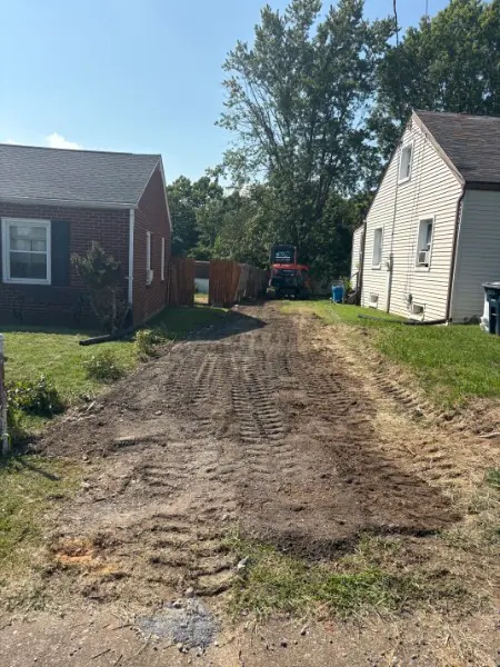 The same side yard after the wall was removed and the ground graded, with a tractor at the back fence.